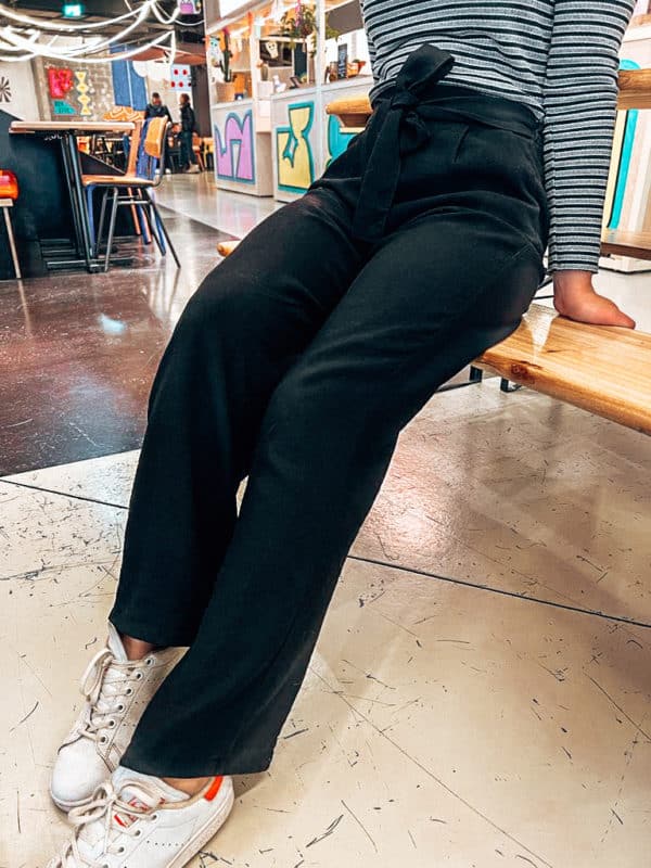 Patron de pantalon fluide ample avec noeud sur le devant. Cousu en noir, vu de face, assis.